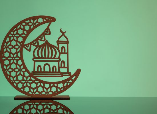 Eid Mubarak concepts with crescent moon in silhouette with mosque against green background