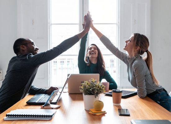 Shot of group of successful young businesspeople holding up their right hands on coworking place.