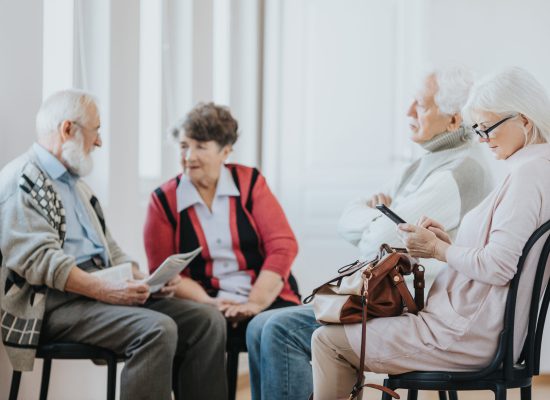 Group of older people talking while sitting in a line to the doctor's office