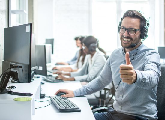 Cheerful,Male,Customer,Service,Operator,Showing,Thumbs,Up,In,Office.