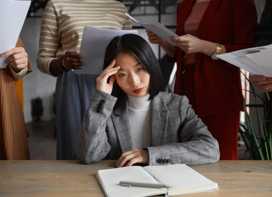 Portrait of annoyed Asian businesswoman looking at camera surrounded by group of people, stress concept, copy space