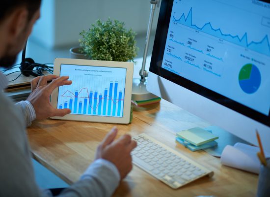 Business person using computer and digital tablet in his work